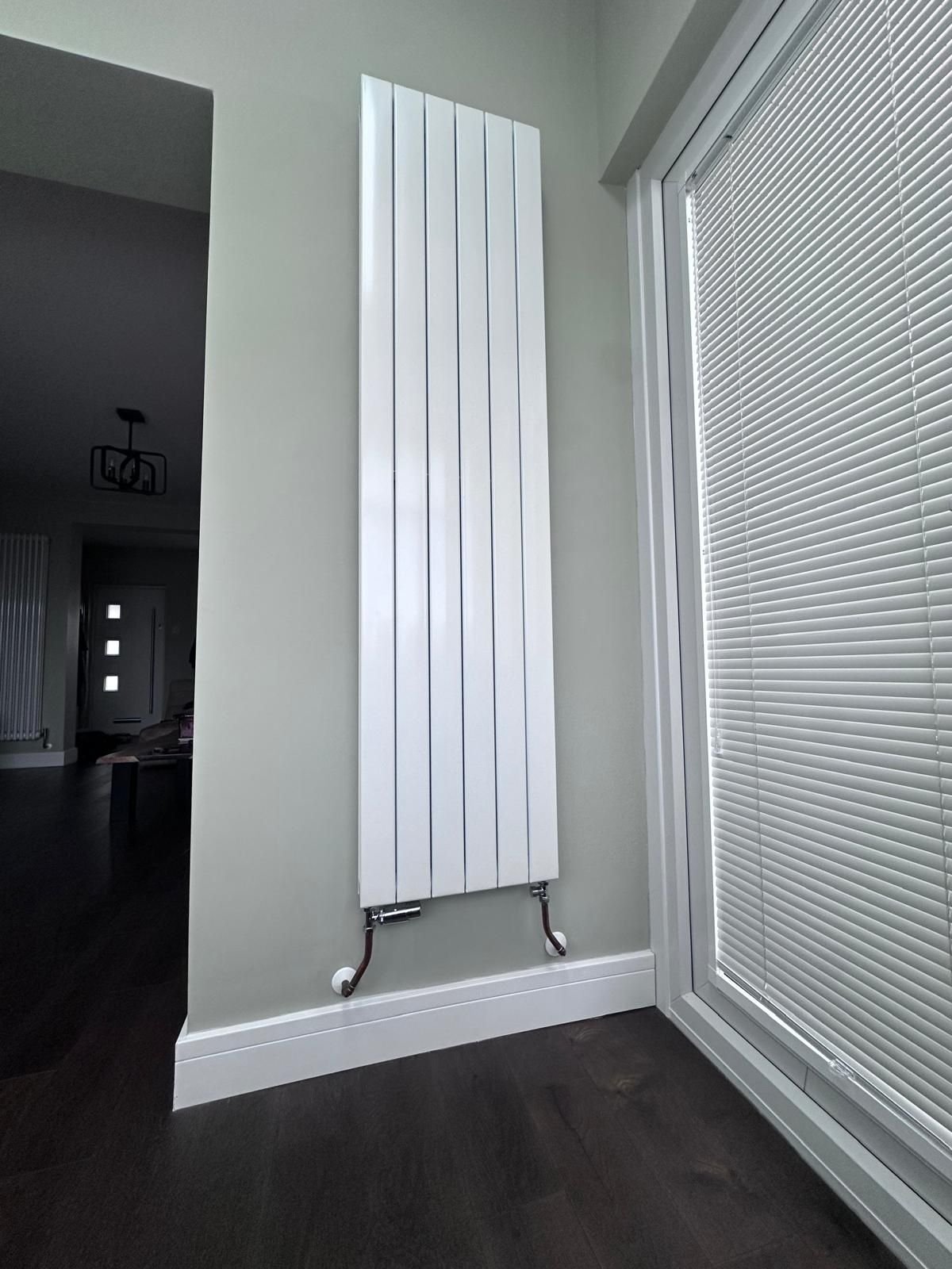 Designer flat panel vertical radiator fitted in a living space