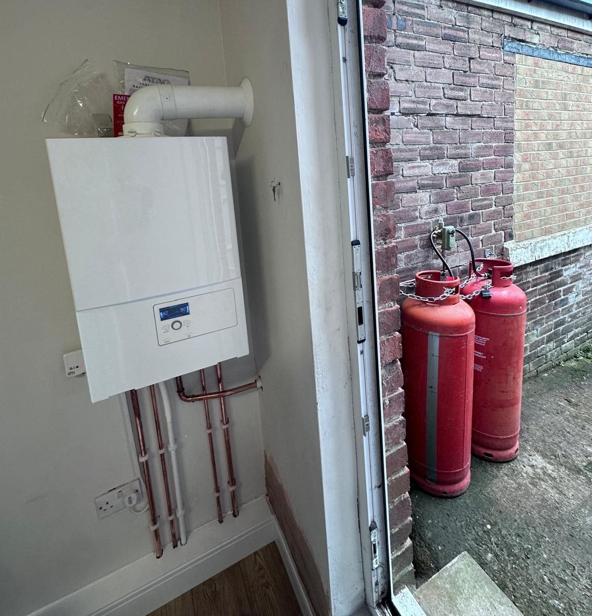 New ATAG LPG boiler with copper pipework and the LPG cylinders chained outside the back door